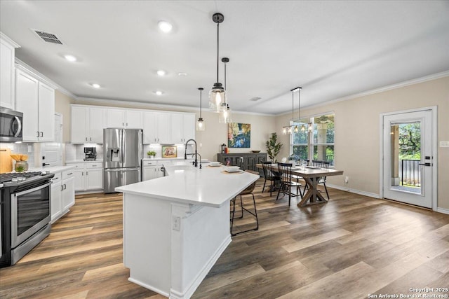 11334 Hill Top Bnd, Helotes, TX 78023 - kitchen featuring appliances with stainless steel finishes, ornamental molding, light countertops, white cabinetry, and an island with sink