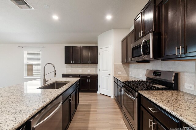 9525 Moon Shine, San Antonio, TX 78254 - kitchen featuring stainless steel appliances, a sink, light wood finished floors, light stone counters, and decorative backsplash