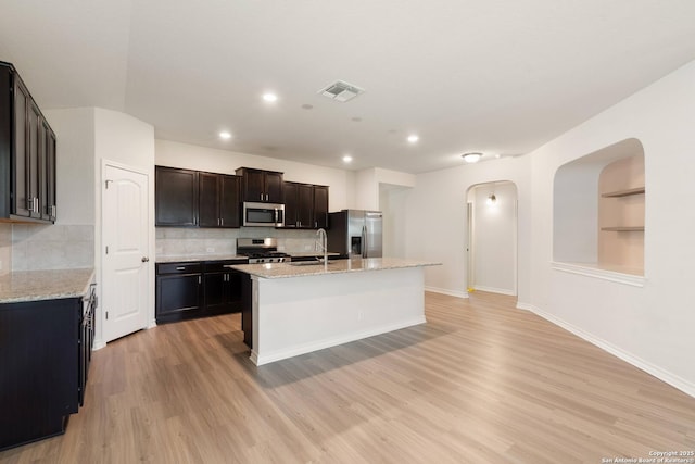 9525 Moon Shine, San Antonio, TX 78254 - kitchen with stainless steel appliances, a sink, arched walkways, light wood finished floors, and decorative backsplash