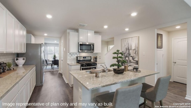 kitchen with stainless steel appliances, dark wood-type flooring, backsplash, a kitchen island with sink, and recessed lighting