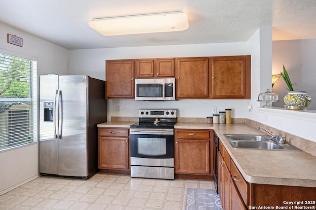 9127 Sycamore, San Antonio, TX 78245 - kitchen featuring stainless steel appliances, a sink, brown cabinetry, and light countertops