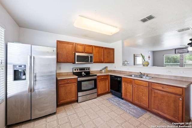 9127 Sycamore, San Antonio, TX 78245 - kitchen with appliances with stainless steel finishes, a sink, brown cabinets, a peninsula, and light countertops