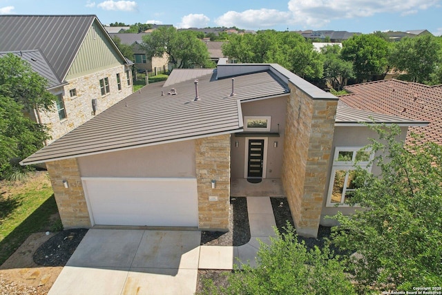view of front of property featuring stone siding, concrete driveway, stucco siding, and a residential view