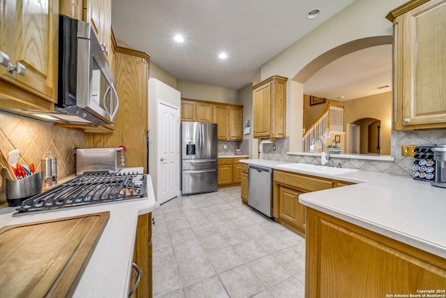 438 Chimney Tops, San Antonio, TX 78260 - kitchen with appliances with stainless steel finishes, a sink, arched walkways, light countertops, and decorative backsplash