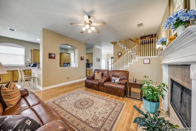 438 Chimney Tops, San Antonio, TX 78260 - living room featuring a fireplace, a ceiling fan, light wood-type flooring, stairway, and arched walkways