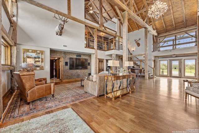 living area featuring high vaulted ceiling, stairs, wood finished floors, beamed ceiling, and a chandelier