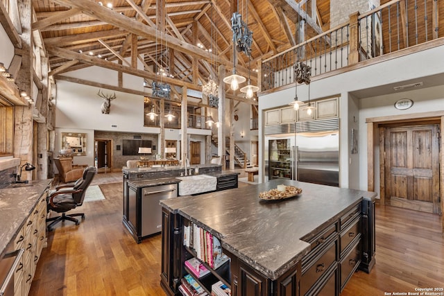 kitchen with stainless steel appliances, high vaulted ceiling, a kitchen island, light wood finished floors, and open floor plan