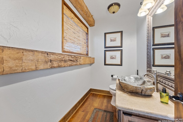 bathroom featuring wood finished floors, toilet, vanity, and baseboards