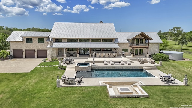 rear view of house with an in-ground hot tub, an outdoor living space with a fire pit, a balcony, a lawn, and a patio area