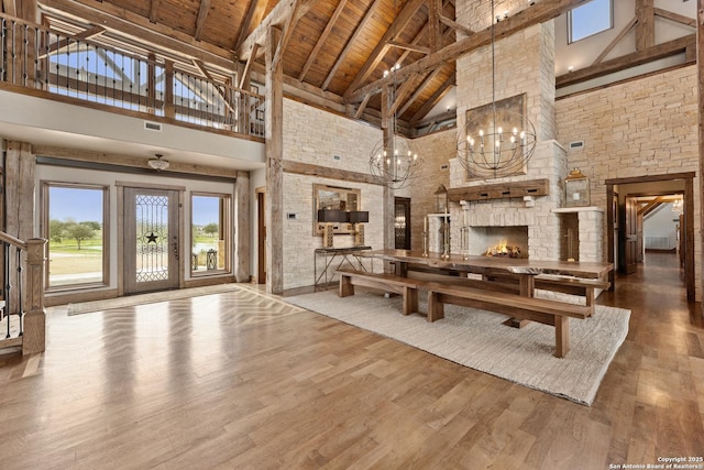 unfurnished living room with high vaulted ceiling, a chandelier, wood finished floors, wooden ceiling, and beam ceiling