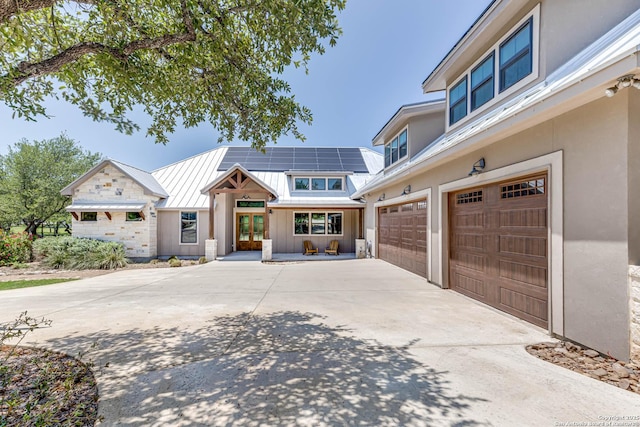 view of front of property with driveway, a garage, metal roof, a standing seam roof, and french doors
