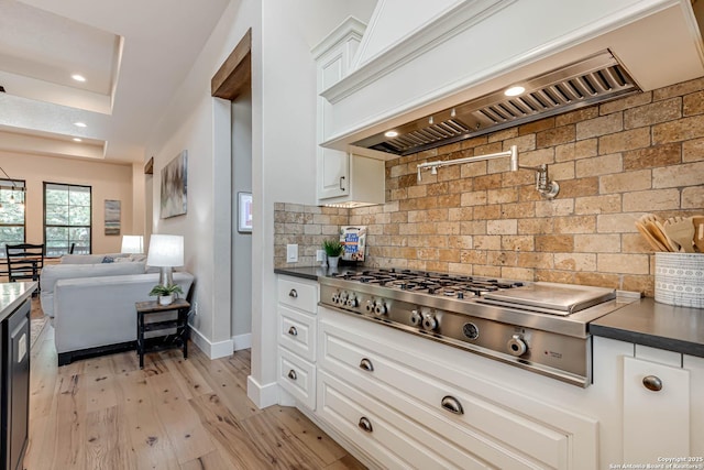 kitchen with premium range hood, stainless steel gas cooktop, backsplash, light wood-style flooring, and white cabinets