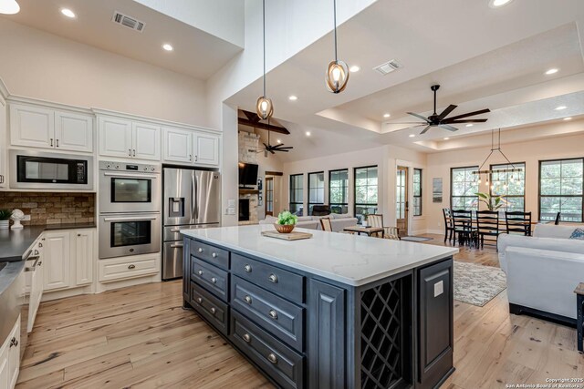 kitchen with stainless steel appliances, a ceiling fan, open floor plan, white cabinets, and recessed lighting