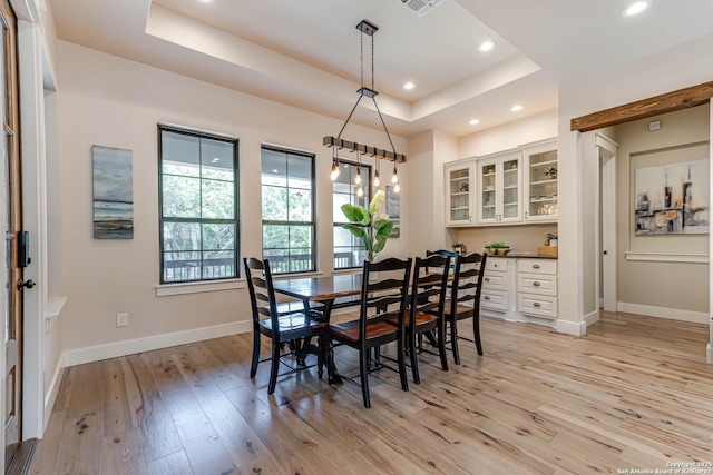 dining area featuring a tray ceiling, light wood-style flooring, baseboards, and recessed lighting