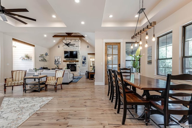 dining area with a ceiling fan, light wood-type flooring, a fireplace, recessed lighting, and a tray ceiling