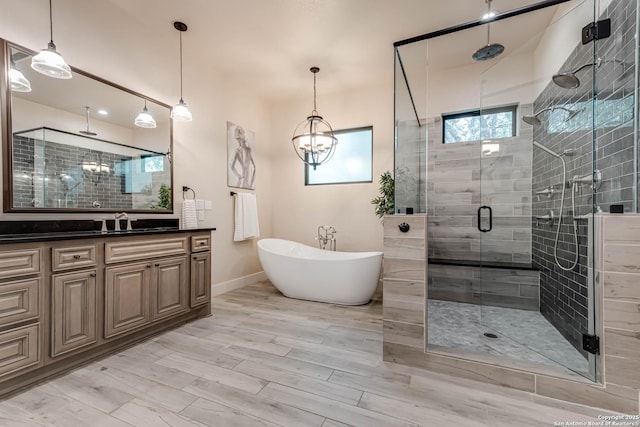 bathroom featuring a stall shower, vanity, a soaking tub, baseboards, and wood finished floors