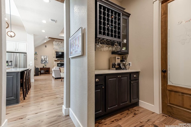 indoor dry bar with stainless steel fridge, light wood-style floors, lofted ceiling, baseboards, and recessed lighting