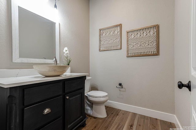 bathroom featuring wood finished floors, baseboards, toilet, and vanity