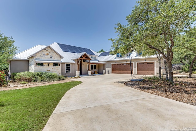 view of front facade featuring a garage, solar panels, driveway, a front lawn, and metal roof