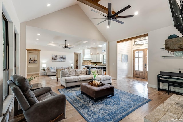 living room with a ceiling fan, high vaulted ceiling, light wood-style flooring, baseboards, and recessed lighting