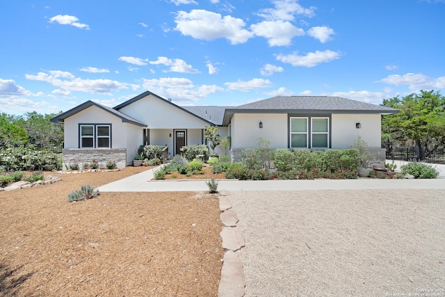 ranch-style home featuring stucco siding, stone siding, and fence