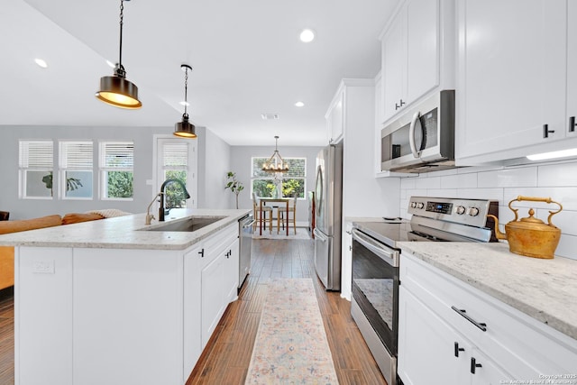 kitchen with stainless steel appliances, a sink, an island with sink, tasteful backsplash, and recessed lighting