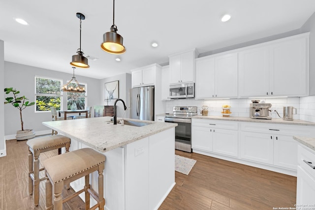 kitchen featuring stainless steel appliances, a sink, tasteful backsplash, a breakfast bar, and light stone counters