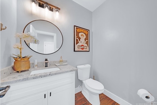 bathroom with wood finished floors, toilet, vanity, and baseboards