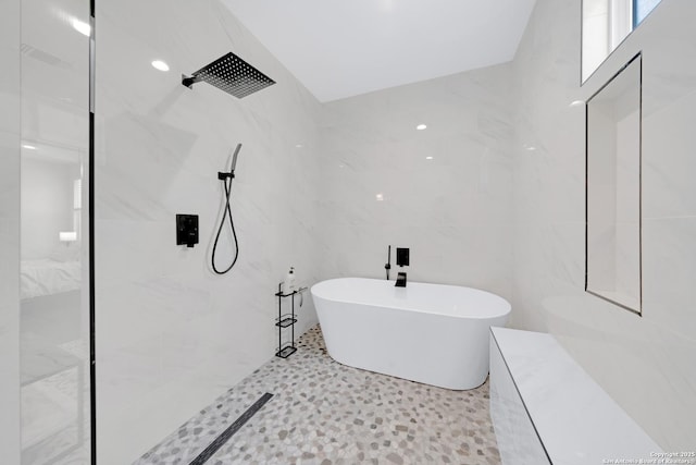 bathroom with a freestanding bath, a shower, and tile walls