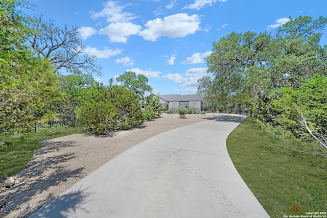 surrounding community with concrete driveway and a yard