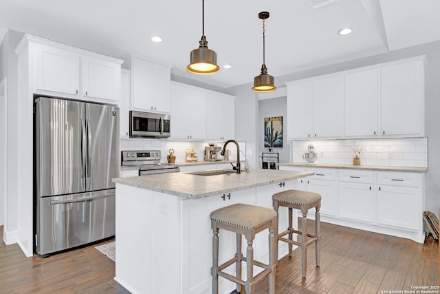 kitchen with stainless steel appliances, a sink, decorative backsplash, recessed lighting, and dark wood finished floors