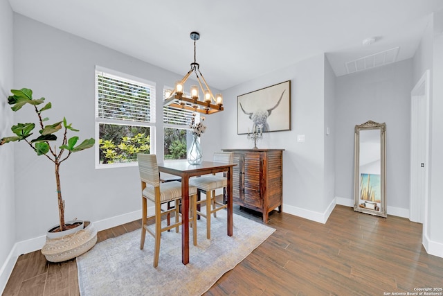 dining space with a chandelier, dark wood-type flooring, and baseboards