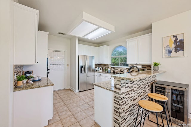 120 Seth Raynor, New Braunfels, TX 78130 - kitchen featuring stainless steel fridge with ice dispenser, a peninsula, wine cooler, decorative backsplash, and white cabinetry