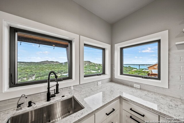 1053 Ledge Path, Canyon Lake, TX 78133 - kitchen with a sink, white cabinets, light stone countertops, and a water view