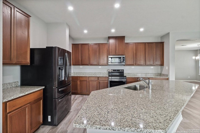 15006 Tethys Way, San Antonio, TX 78245 - kitchen with appliances with stainless steel finishes, a sink, light wood-type flooring, a large island with sink, and brown cabinetry