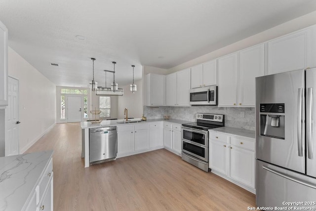 8651 Eagle Peak, Helotes, TX 78023 - kitchen with appliances with stainless steel finishes, a sink, decorative backsplash, light wood finished floors, and white cabinetry