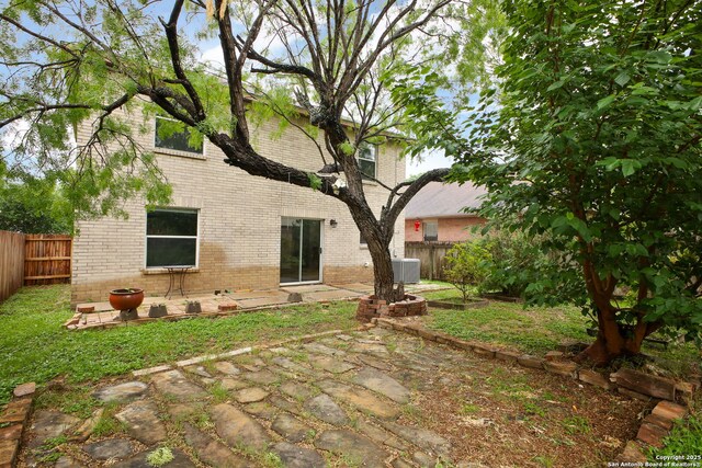 rear view of house with brick siding, a fenced backyard, and a patio area