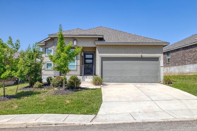 view of front of property with an attached garage, stucco siding, concrete driveway, a front yard, and roof with shingles