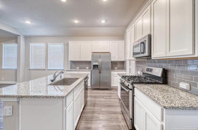 kitchen with appliances with stainless steel finishes, a sink, white cabinets, tasteful backsplash, and recessed lighting