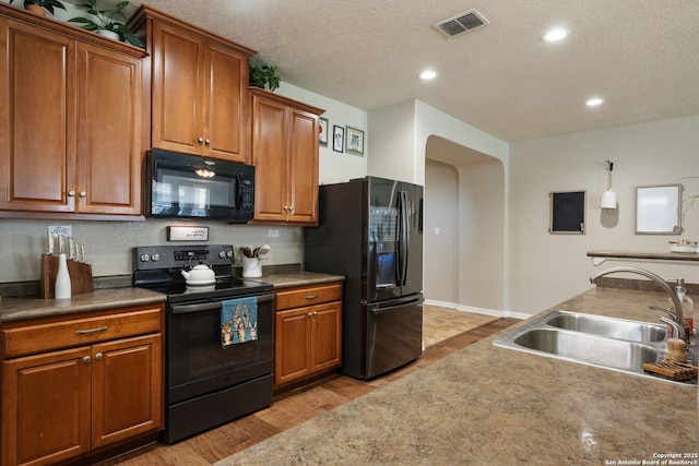 208 Cold Riv, Boerne, TX 78006 - kitchen with black appliances, a sink, light wood finished floors, brown cabinets, and a textured ceiling