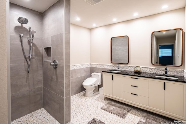 115 Wickford, Castle Hills, TX 78213 - bathroom featuring toilet, tiled shower, tile walls, wainscoting, and double vanity