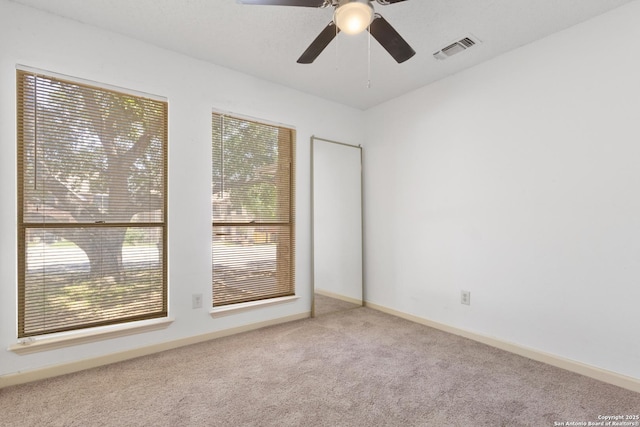 empty room featuring carpet floors, a ceiling fan, and baseboards