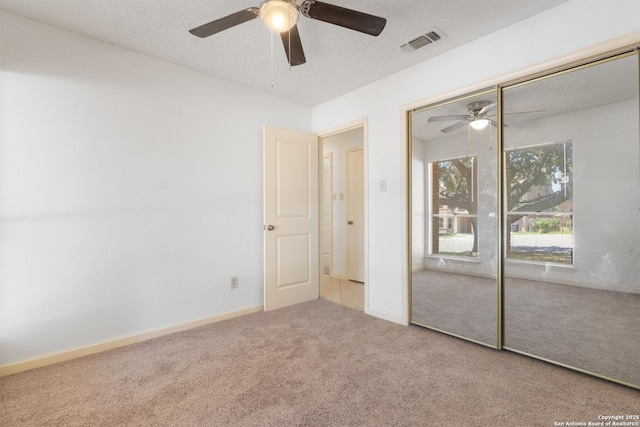 unfurnished bedroom with carpet floors, ceiling fan, a closet, a textured ceiling, and baseboards