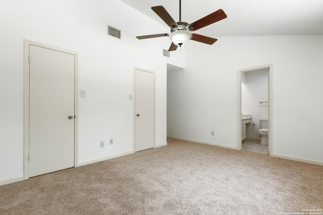 unfurnished bedroom with light carpet, high vaulted ceiling, ensuite bathroom, and baseboards