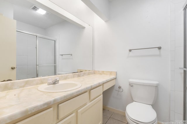 bathroom featuring tile patterned flooring, toilet, a shower with door, and vanity