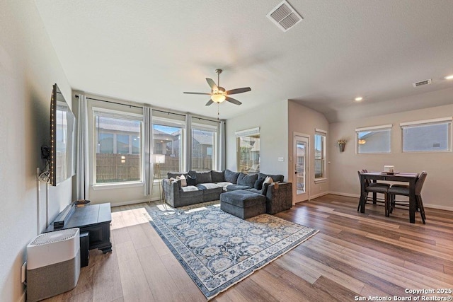 living area with a ceiling fan, wood finished floors, healthy amount of natural light, and recessed lighting