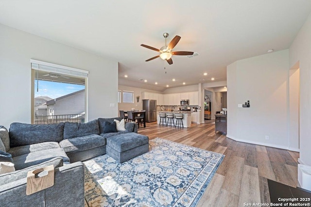 living area featuring light wood finished floors and ceiling fan