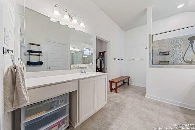 bathroom featuring walk in shower, vanity, a walk in closet, baseboards, and tile patterned floors