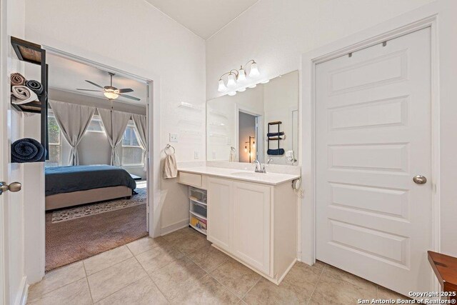 ensuite bathroom with vanity, tile patterned flooring, a ceiling fan, and baseboards