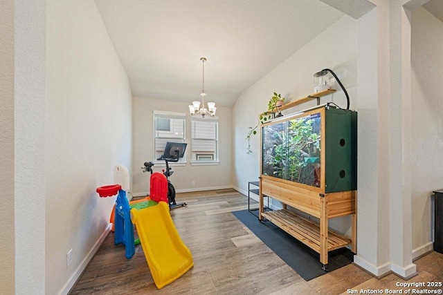 rec room with wood finished floors, baseboards, and a chandelier